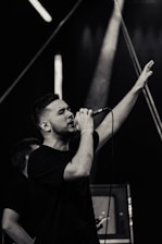 Elegant male singer performing passionately on stage with warm, dark lighting.