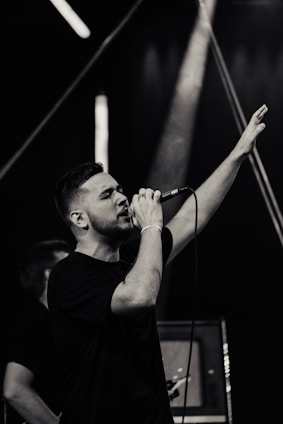 Elegant male singer performing passionately on stage with warm, dark lighting.