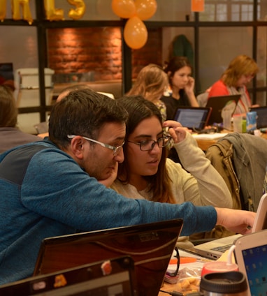 a group of people sitting at a table with laptops