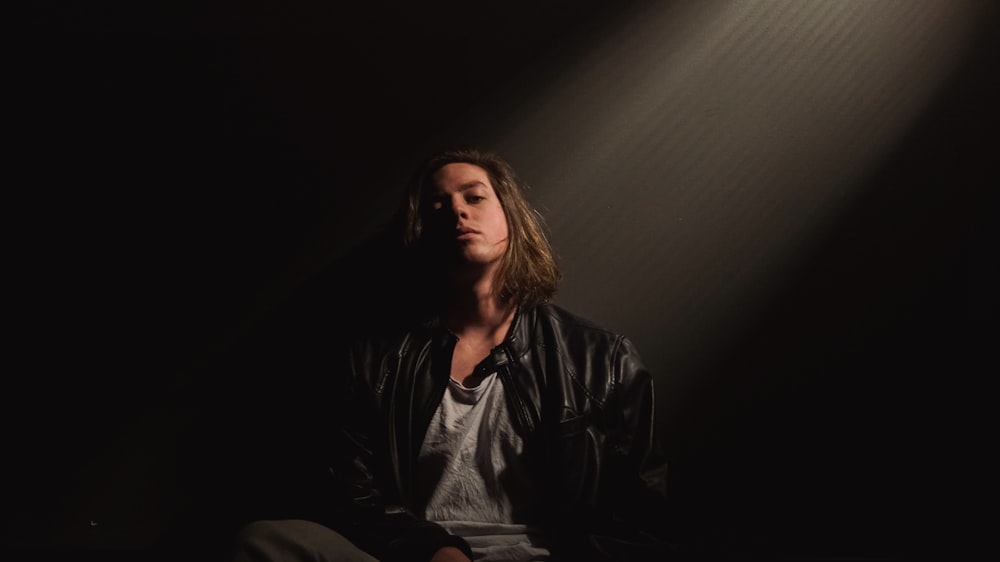 man sitting on front of gray wall