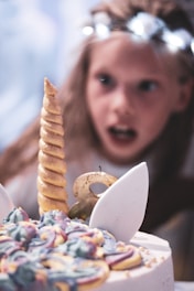 A joyful child holding a unicorn-themed invitation.