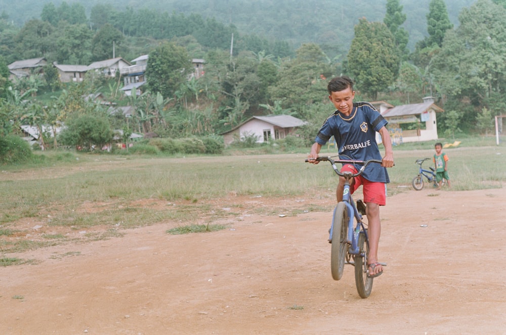 boy rides blue bike on dirt road