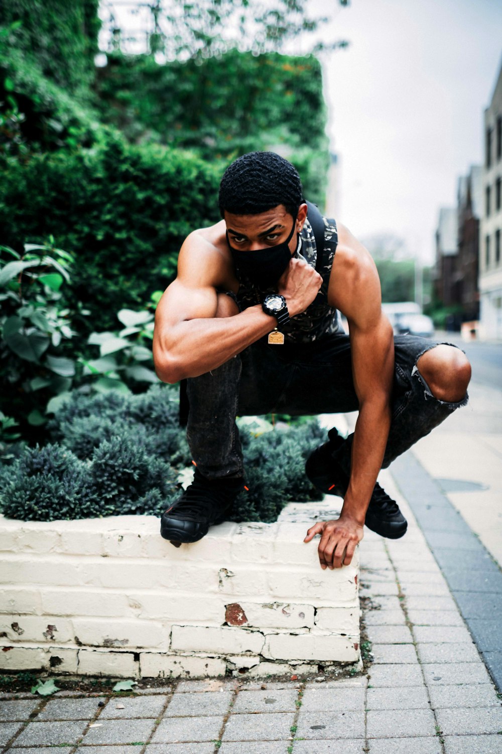 man squatting on concrete wall