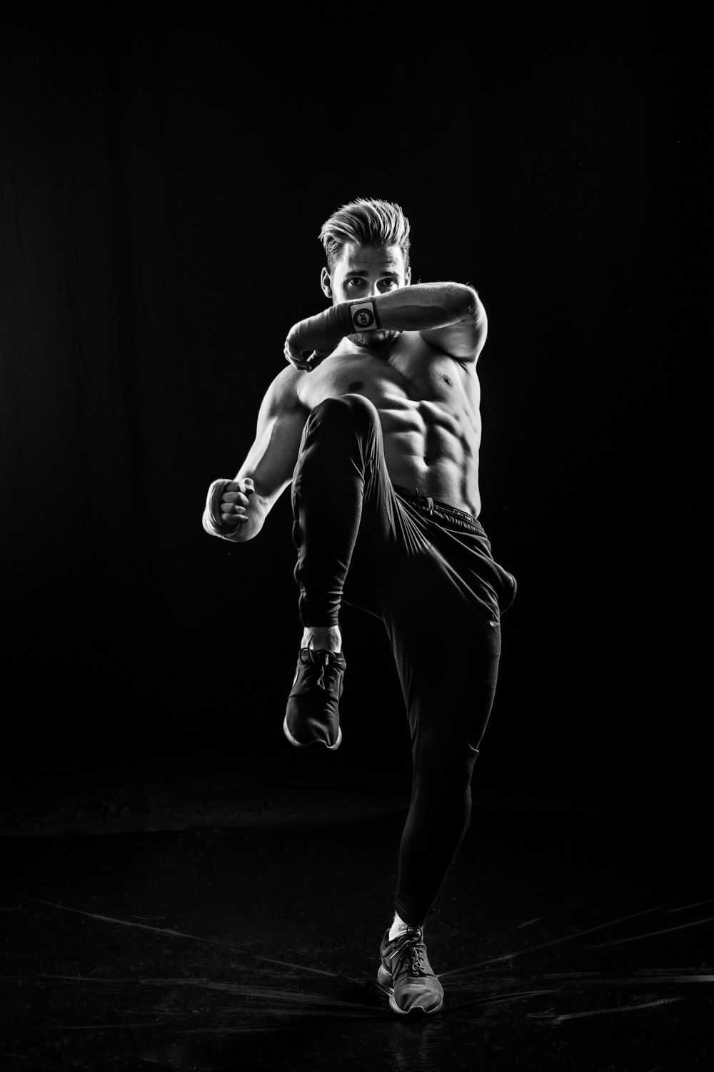 grayscale photo of man wearing pants kicking