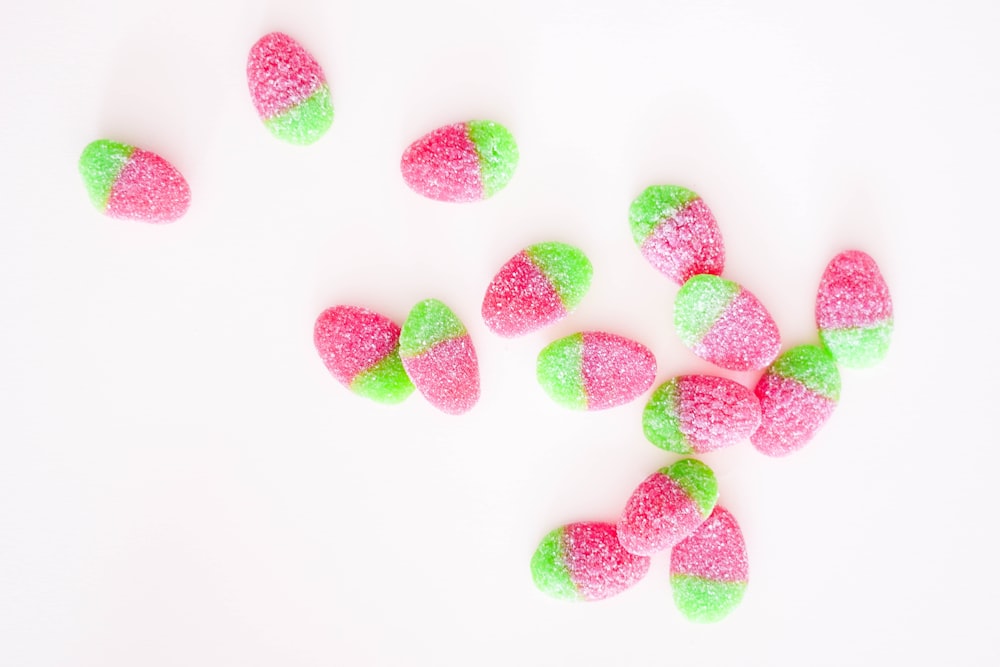 red and green sugar coated candies on white surface