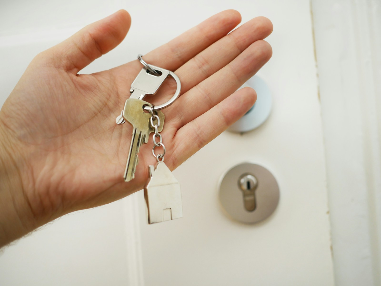 Hand holding up house keys with door in behind Find the value of your home