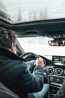 A person enjoying music in a car, with a scenic background and a focus on the radio system.