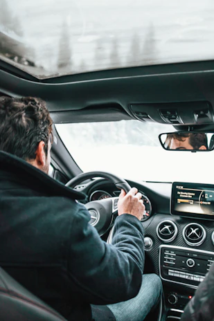 A driver enjoying music through a premium car radio system, the deep crimson glow reflecting softly on the steering wheel.