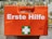 A bright orange first aid box mounted against a textured brick wall. The box features the words 'Erste Hilfe' in bold white letters, along with a green cross symbol, indicating first aid supplies.