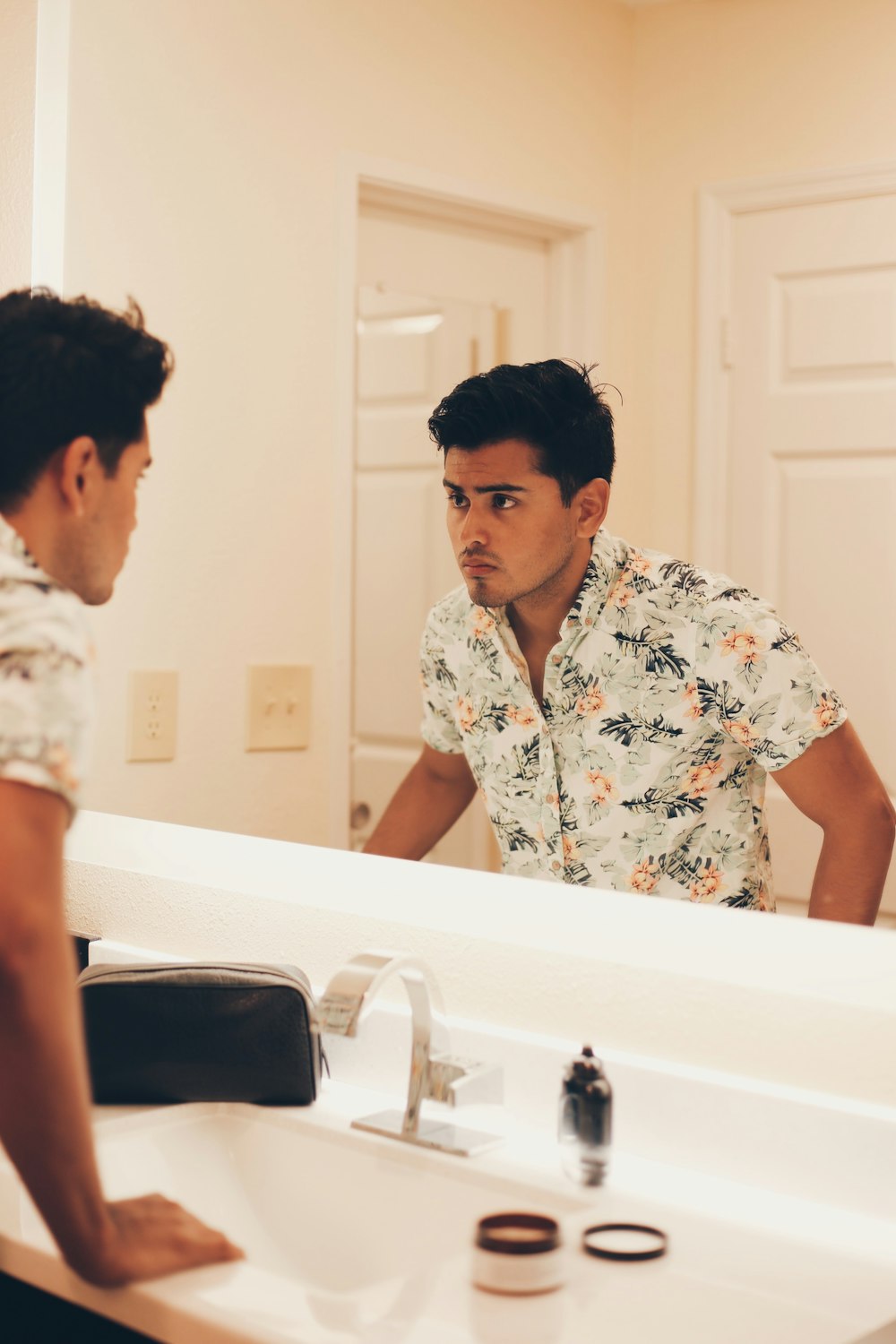 man wearing floral dress shirt standing and facing mirror