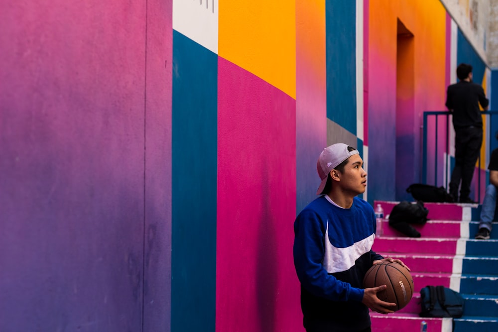 man in blue and white Nike crew-neck sweater holding basketball