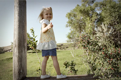 A little girl balancing carefully on a beam with a big smile.