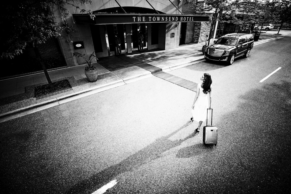 greyscale of women pulling luggage bag