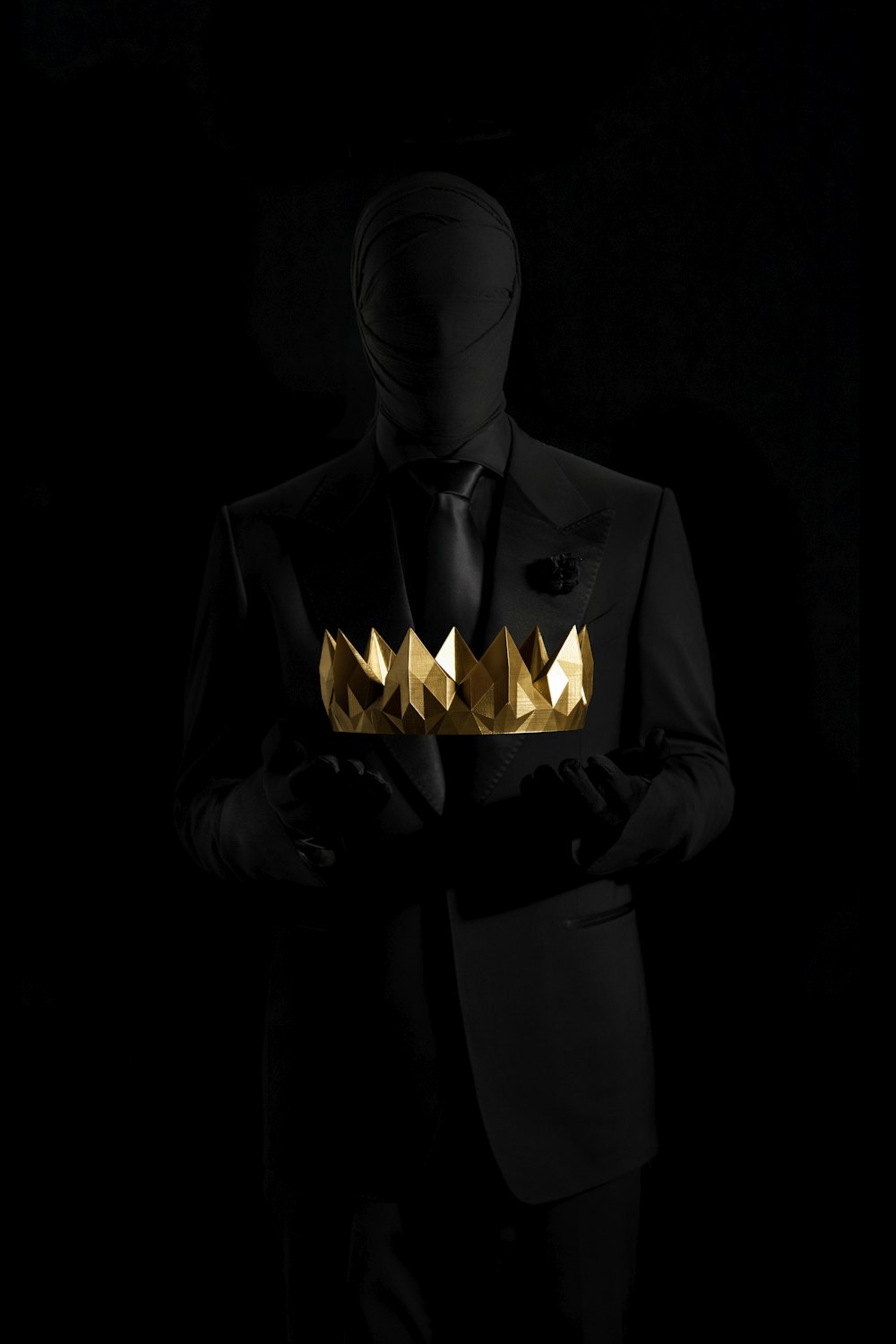 person in black suit jacket holding gold crown
