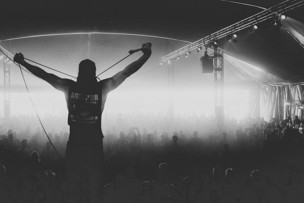 man standing on stage raising his hands with microphone