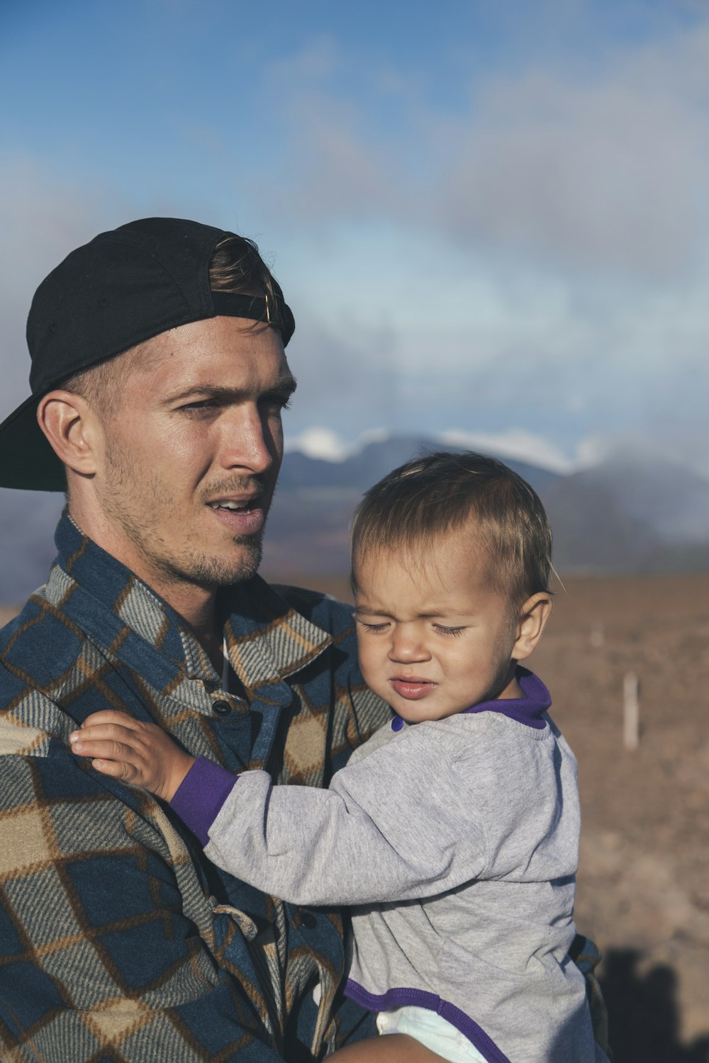 shallow focus photo of man carrying baby