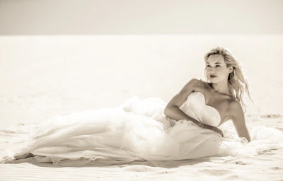 A serene beach scene with a model in an elegant Esencia de Musa swimsuit, sunlight highlighting the fabric's texture.