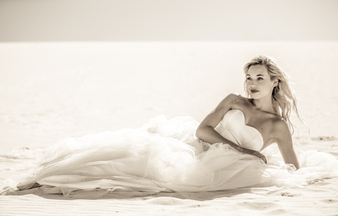 A serene beach scene featuring a flowing geo closet dress in white, with golden sunlight and gentle waves.