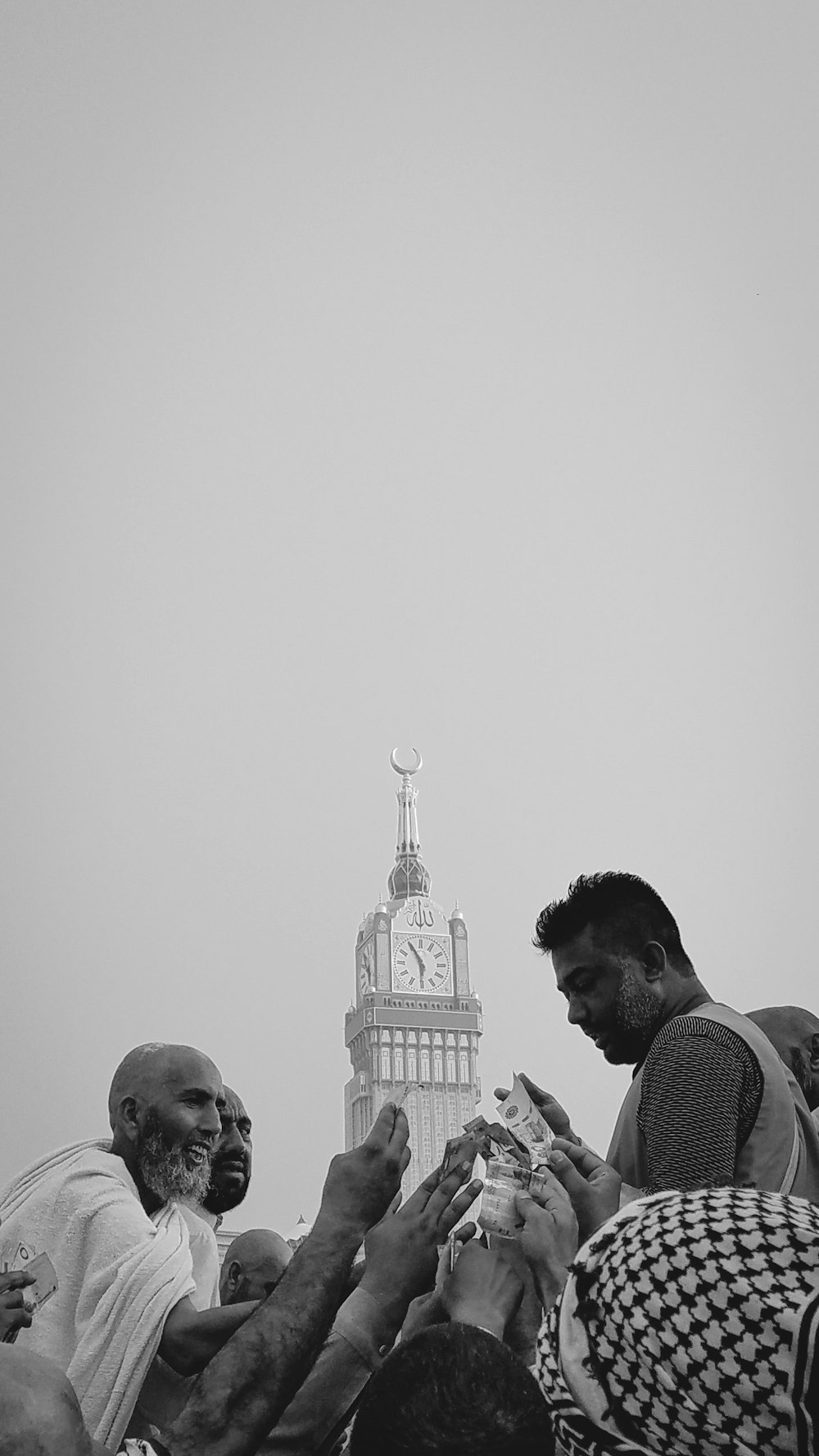 a group of people standing around each other in front of a clock tower