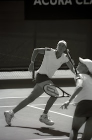 Women practicing tennis drills together on an outdoor court under sunny skies.