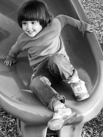 Close-up of a child happily sliding down a vibrant FRP slide in a safe, outdoor playground setting.