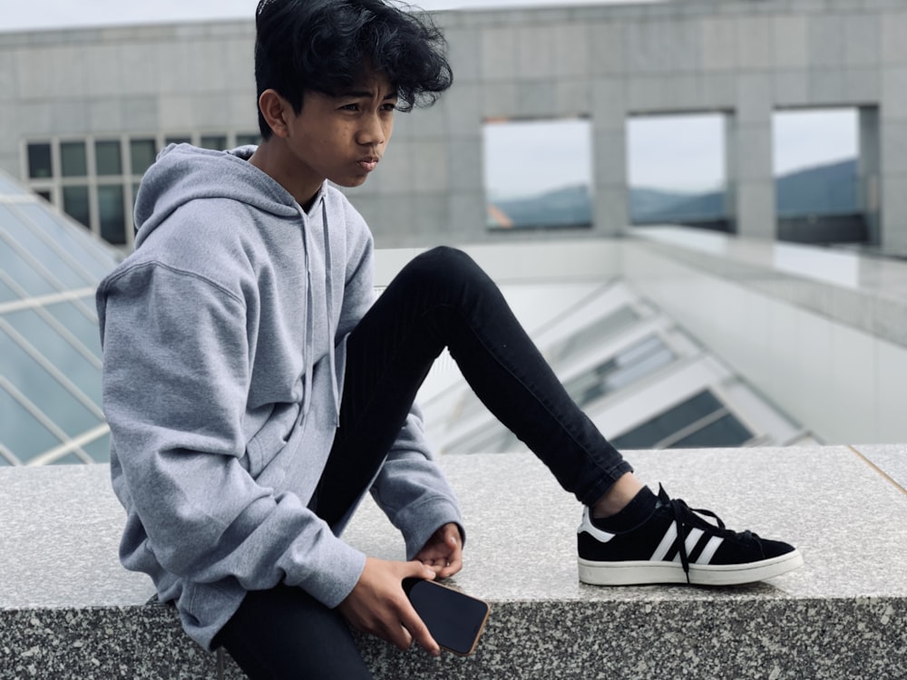 boy sitting on gray concrete