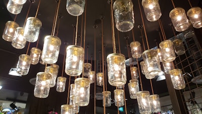 Multiple glass jar light fixtures hang from the ceiling with visible bulbs inside, creating a warm and inviting atmosphere. The jars are suspended with ropes, adding a rustic touch to the modern lighting design.