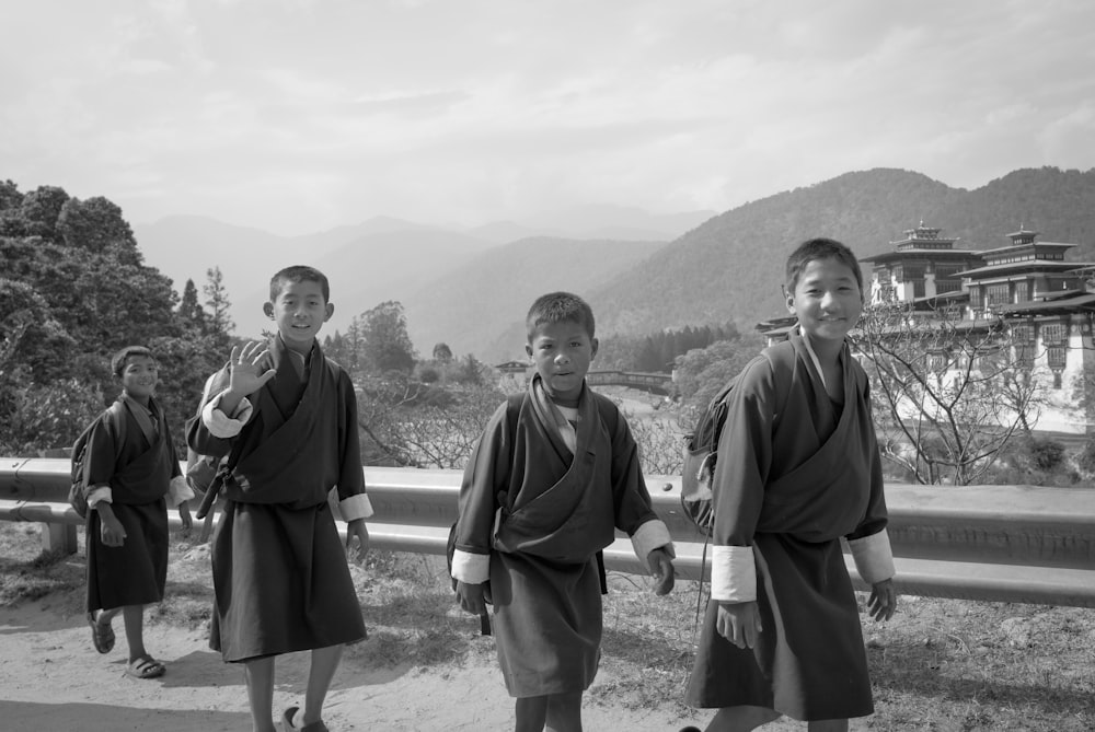grayscale photography of four wavingand walking boys during daytime