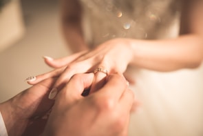 A close-up of hands exchanging wedding rings, focusing on the delicate details.