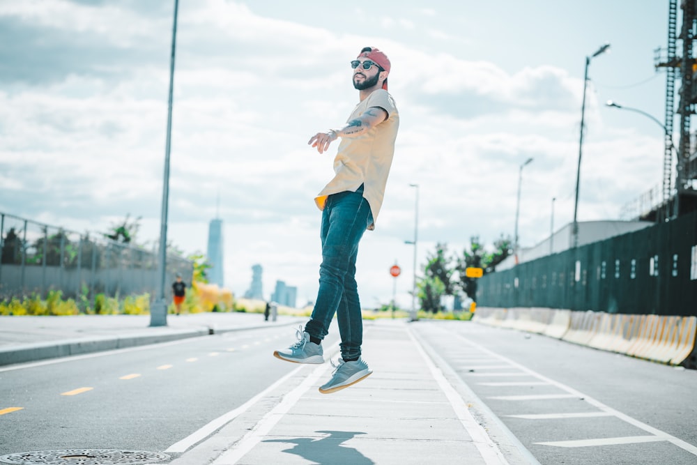 man jumping near road under white skies during daytime