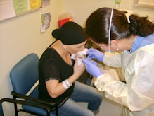 A smiling healthcare worker attending to a patient in a rural village setting.