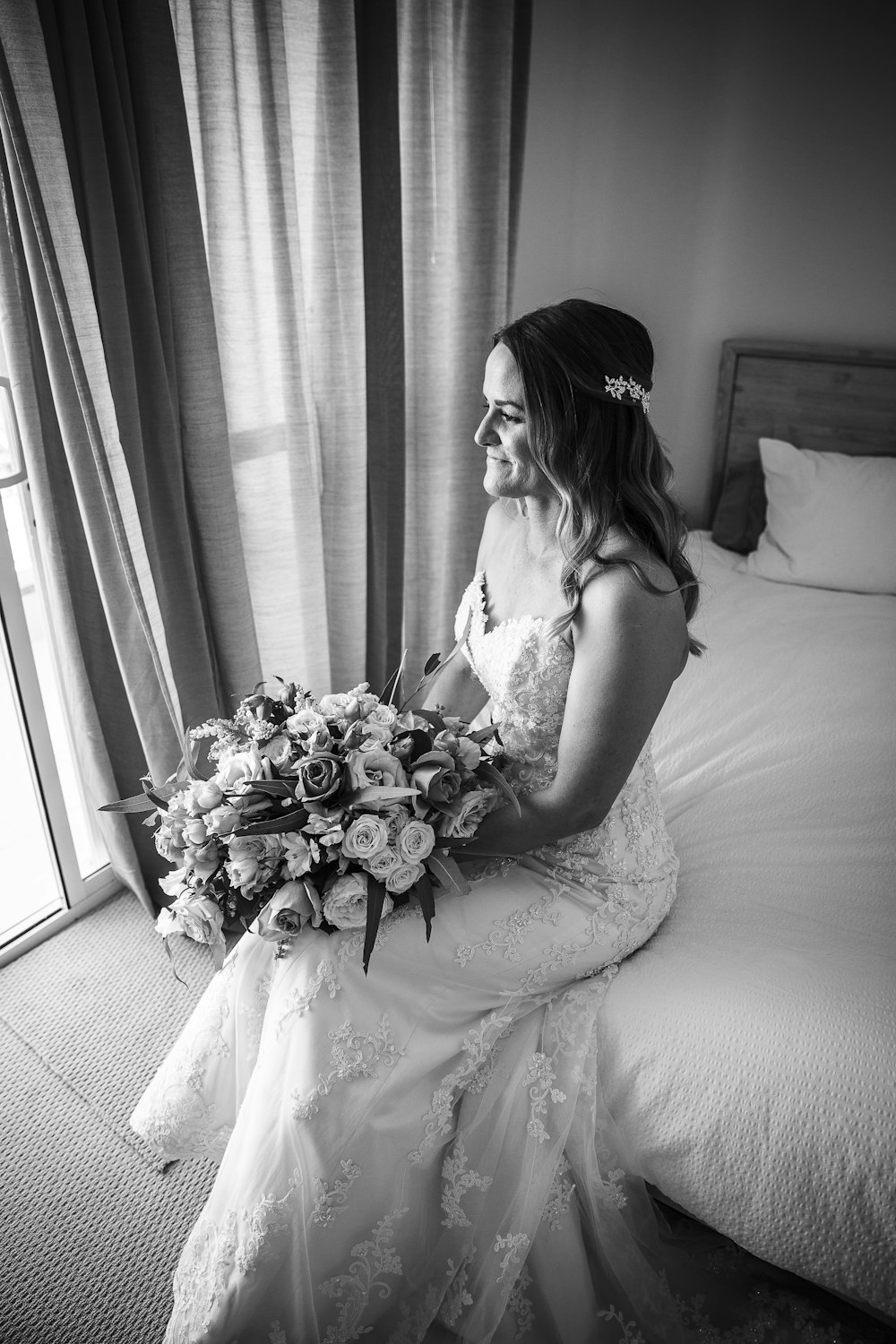 grayscale photography of woman siting on bed