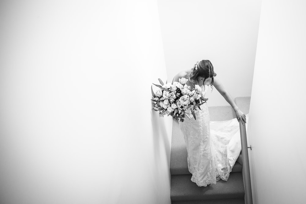 grayscale photography of woman wearing wedding gown walking on steps