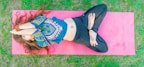 An active person practicing yoga outdoors on a pink mat.