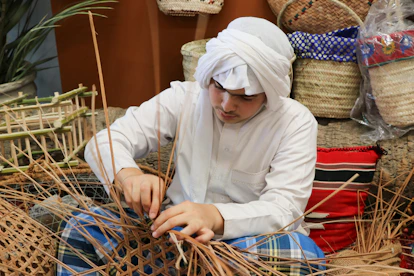 An artisan carefully weaving a traditional fabric surrounded by handcrafted tools and materials.