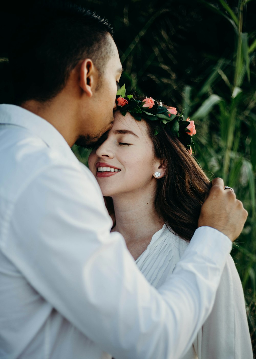 man kissing woman on forehead