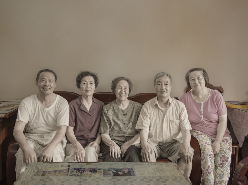 four persons sit on sofa in front empty coffee table