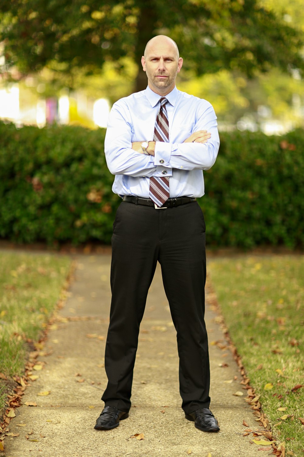 man in white dress shirt standing on concrete pathway