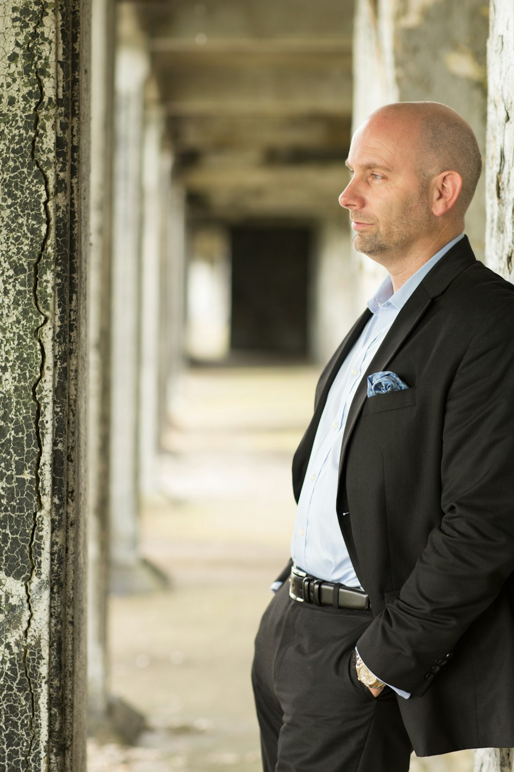 naman in black suit leaning on wall