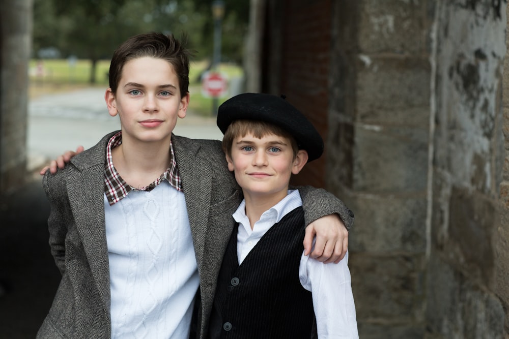 two boys beside concrete wall