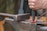 A hand is holding a chisel and hammering a red-hot piece of metal on an anvil, illustrating metalworking in progress.