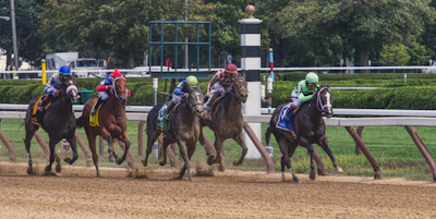 A vibrant scene of horses sprinting down the track with enthusiastic spectators in the stands.