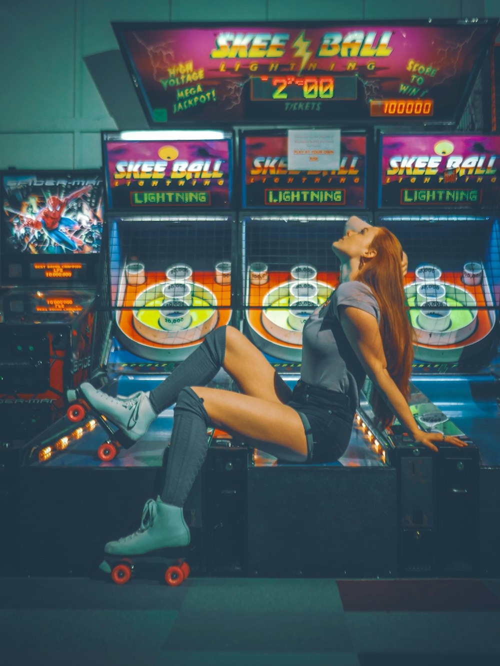 woman wearing gray shirt sitting on Skee Ball game cabinet