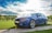 A clean, shiny car parked in a driveway with a blue sky in the background.