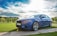 A clean, shiny car parked in a driveway with a blue sky in the background.