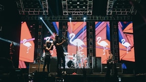 The band rocking out in front of a gleaming pink Cadillac on stage.