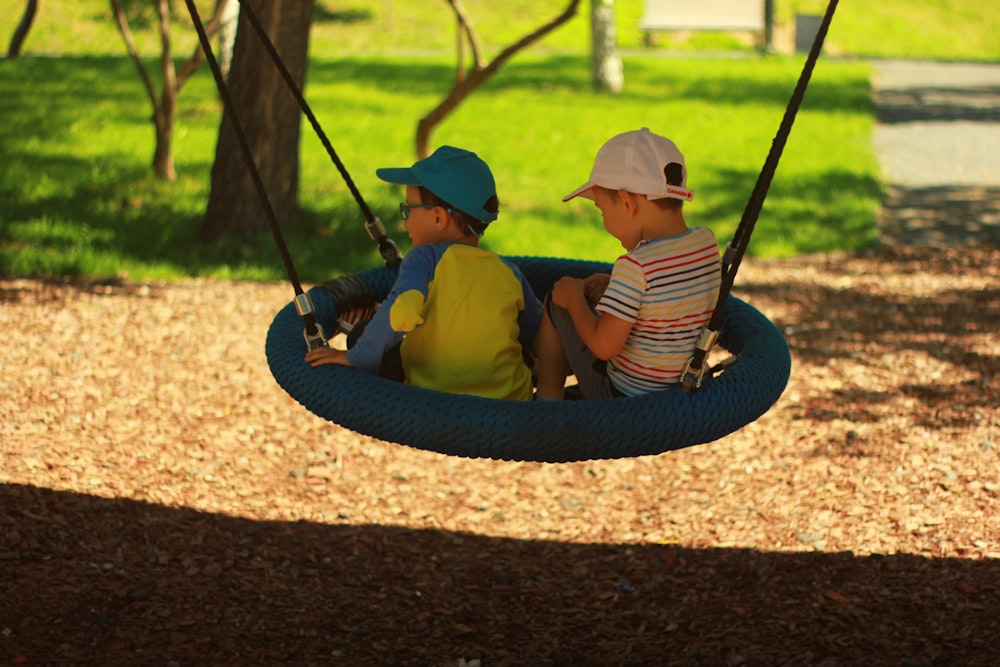 two boys sitting on swing