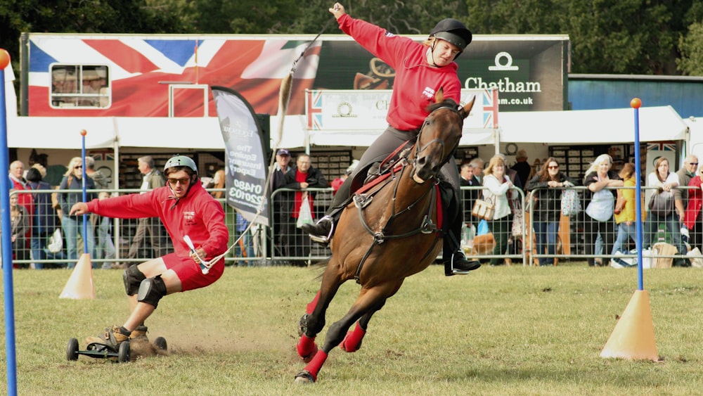 uomo che indossa un pullover rosso che cavalca su un cavallo marrone