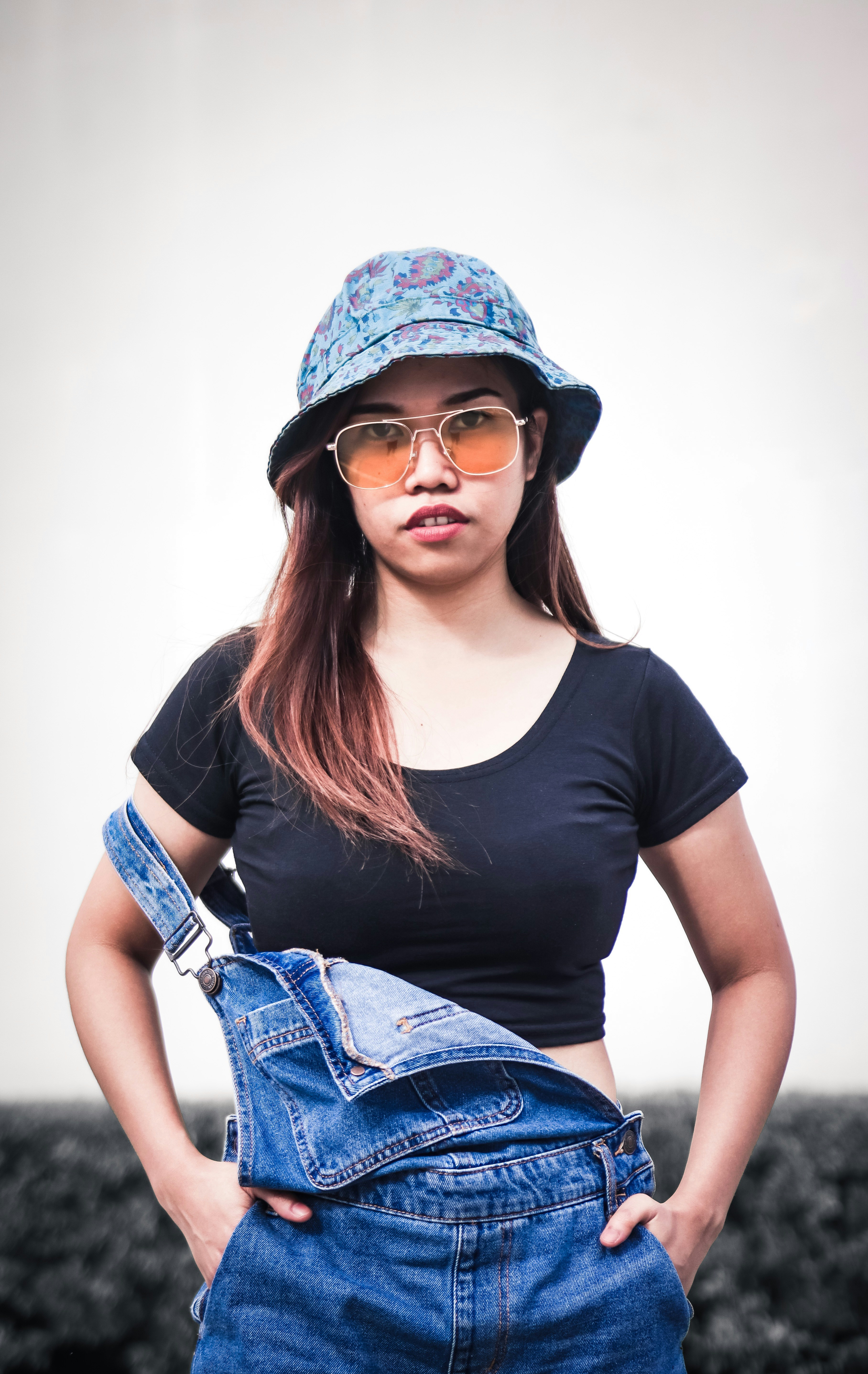 woman smiling with both hands in her overalls's pockets