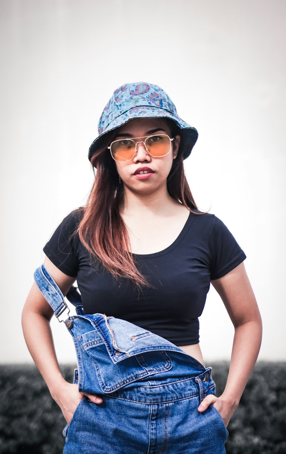 woman smiling with both hands in her overalls's pockets